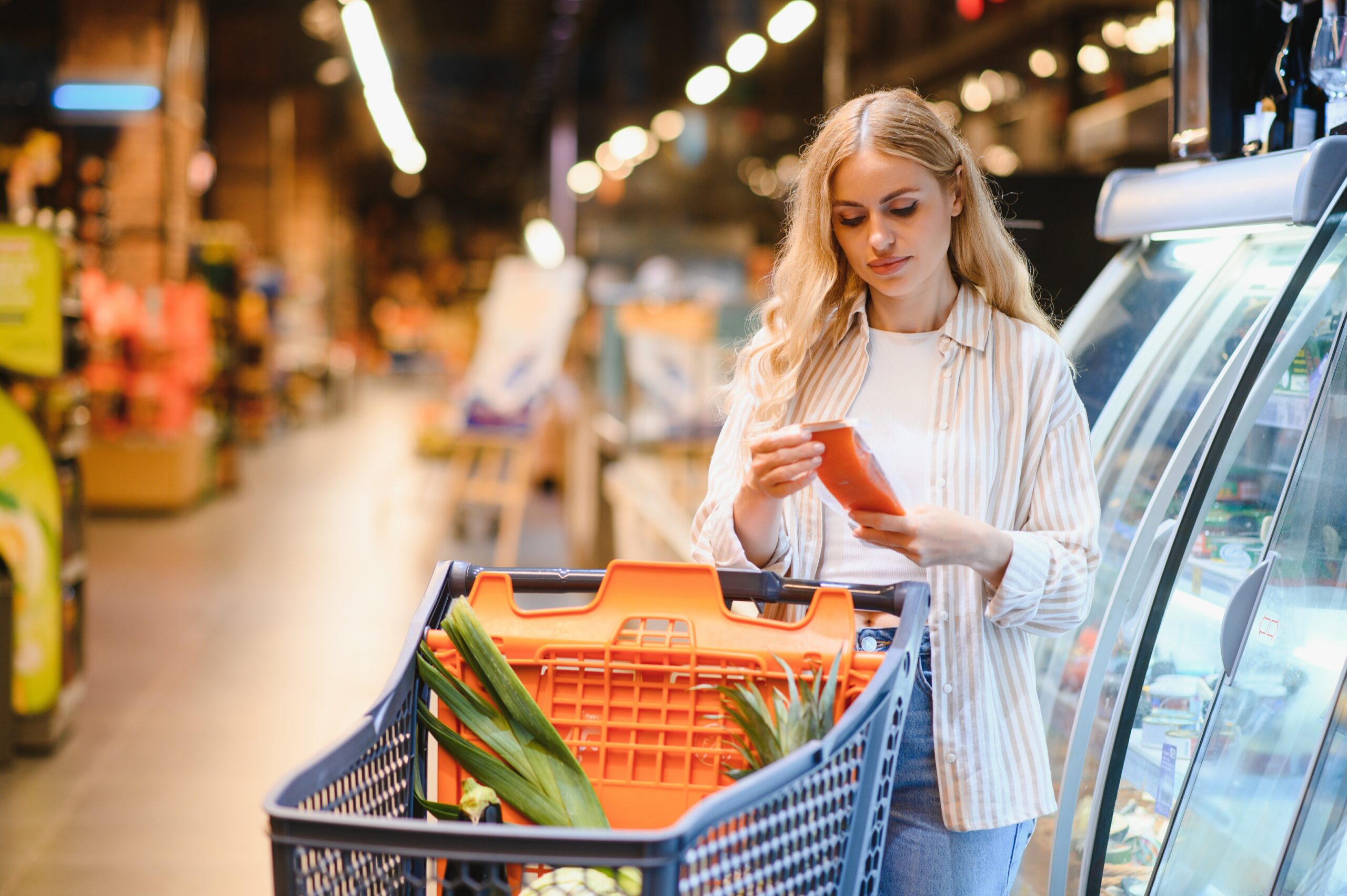 young caucasian woman buying frozen fish, groceries in a supermarket, mall, grocery store.