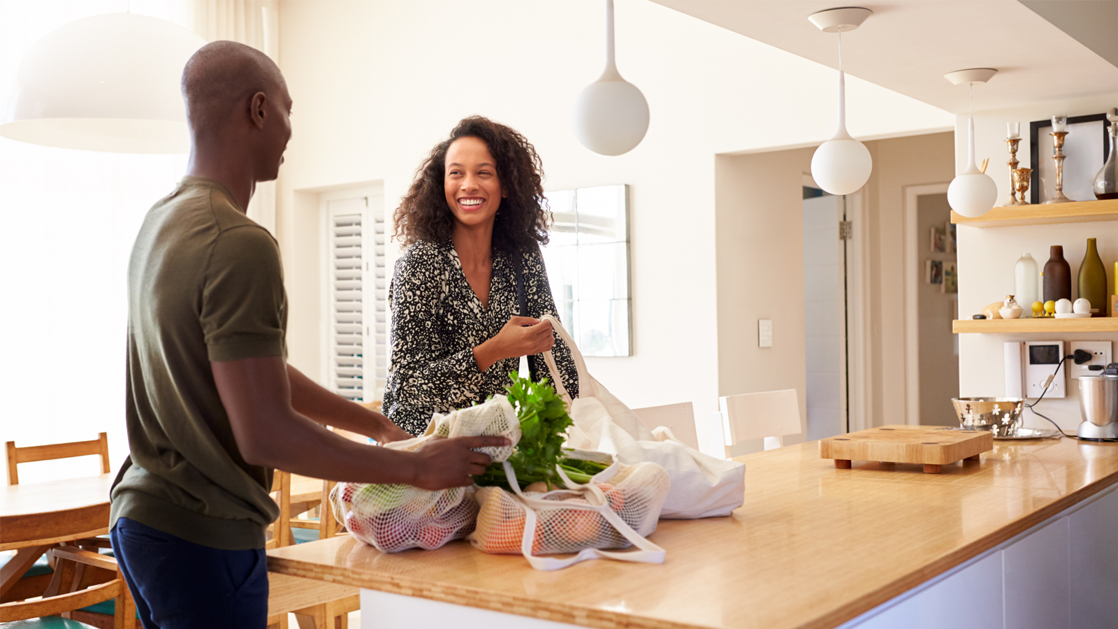 Couple Returning Home From Shopping Trip Unpacking Plastic Free Grocery Bags