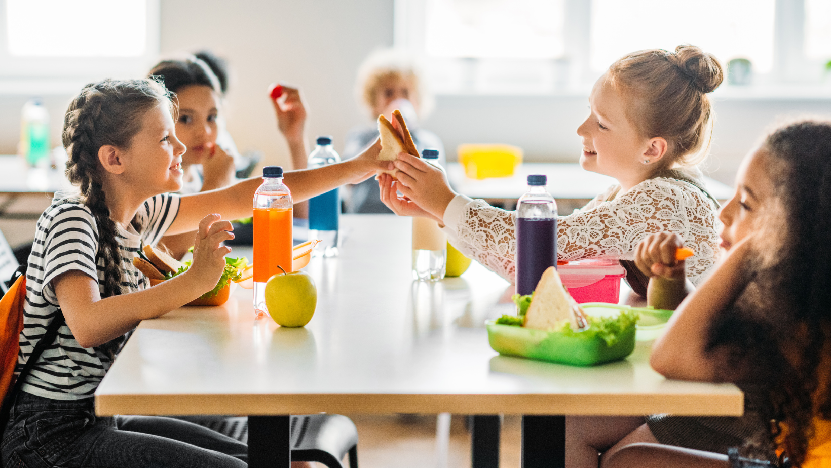 Small kids on a table eating school lunch